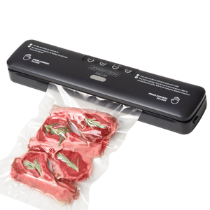 Black JORES TECHNOLOGIES® vacuum sealing machine for home use on a white background. The machine is sealing an embossed vacuum bag filled with lamb chops and rosemary.