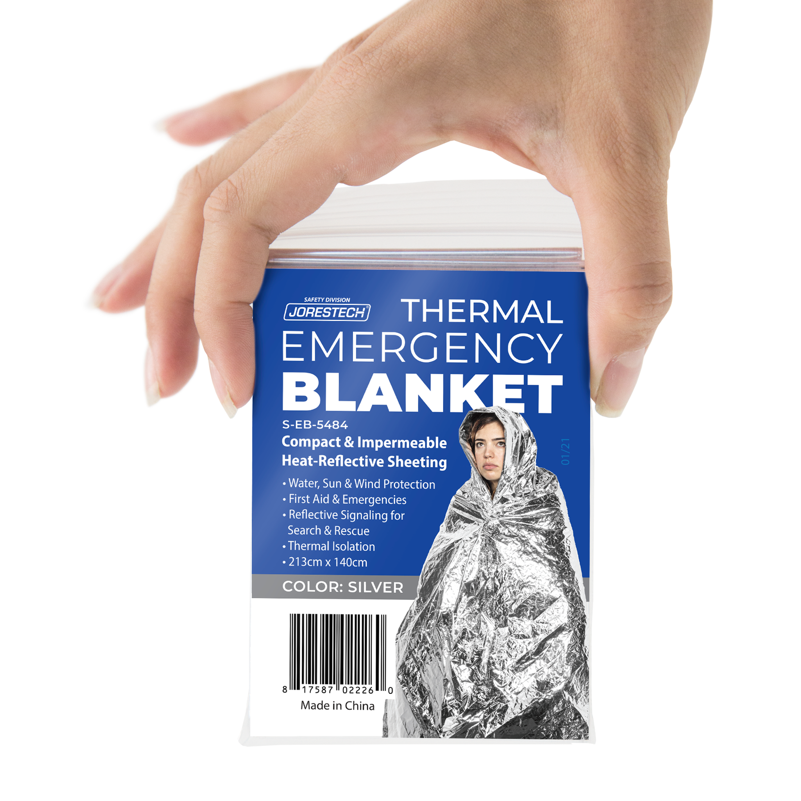 Hand of a person holding one thermafoil emergency blanket in its zip-lock bag with a sticker that reads: Compact and impermeable heat reflective sheeting for water, sun and wind protection.  