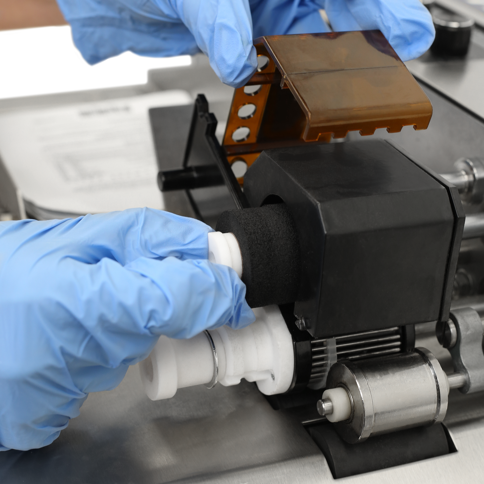 Close up showing the hand of a person inserting a black hot ink roll into the hot ink roll coder.  It also shows the type holder in place