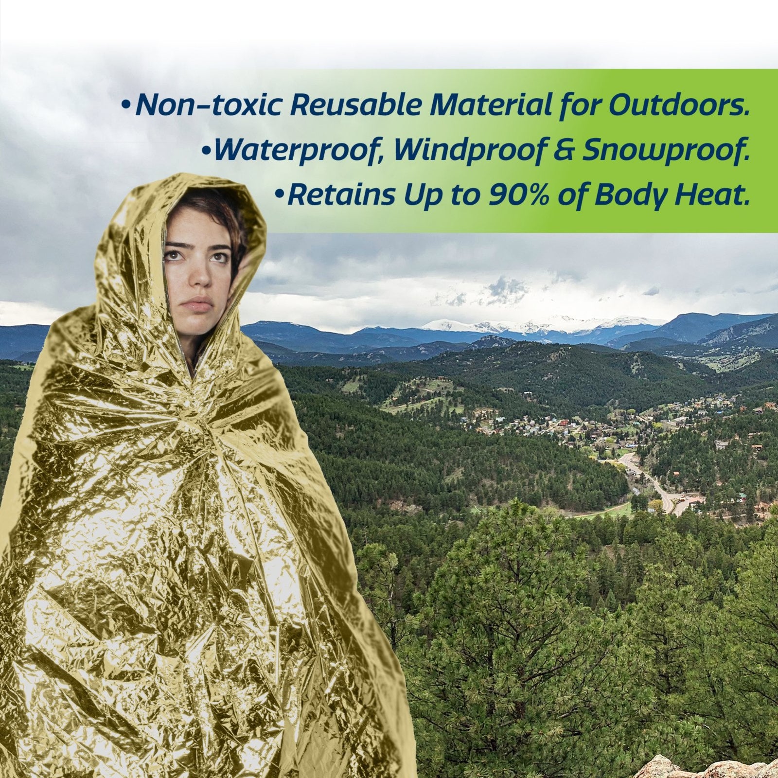 A person using an emergency blanket for wind, cold and sun protection on top of a mauntain. Text reads: Non toxic reusable material for outdoors. waterproof, windproof &snow-proof. retains up to 90% of body heat.