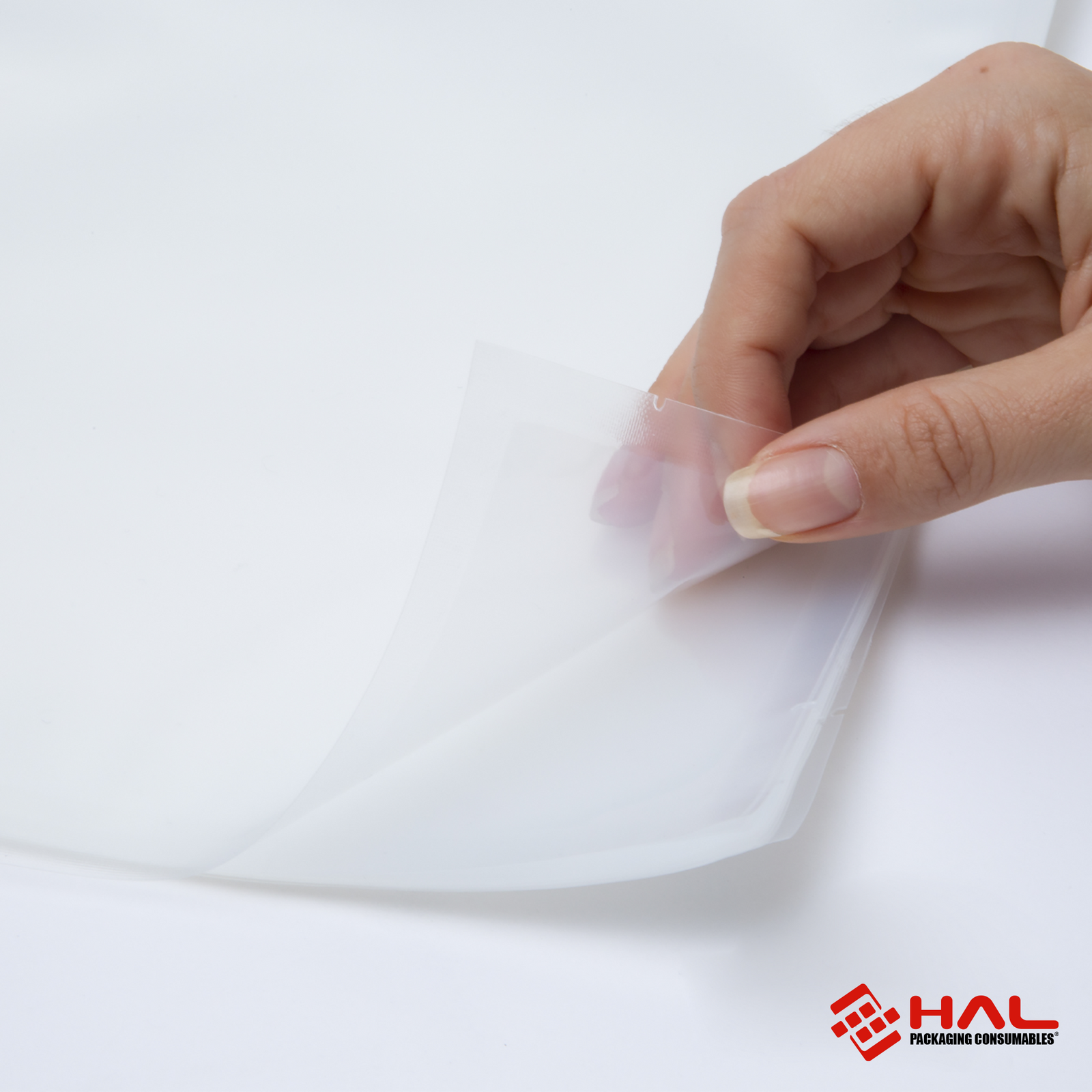 Image of the hands of a woman opening a clear bag to show the material of the HAL vacuum sealer bags over white background