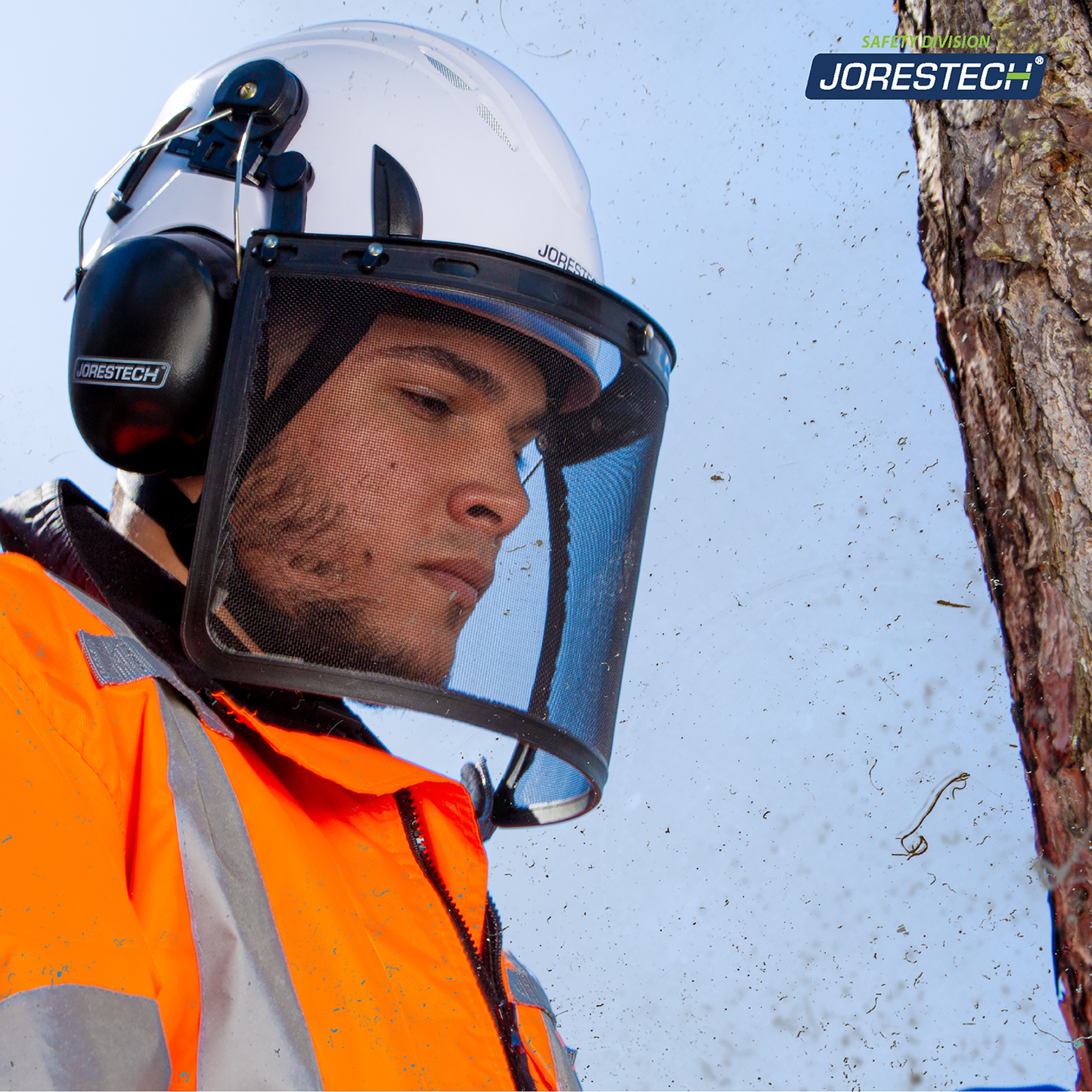 An arborist cutting some branches while wearing the white jorestech ventilated safety helmet with the iron mesh face shield and earmuff attachments.