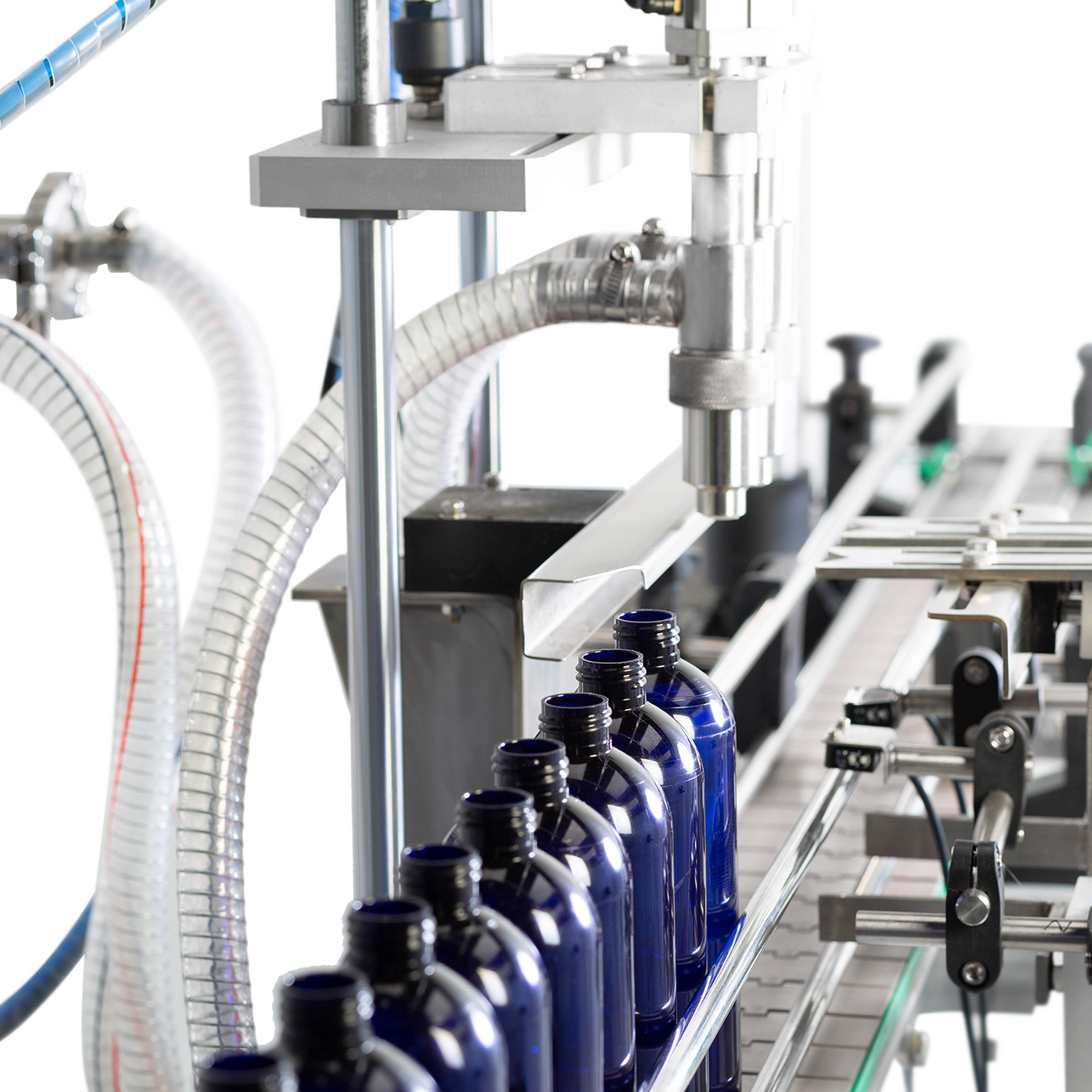 Closeup of the two heads of the paste filling system about to dispense high viscosity product into a line of 250ml blue bottles